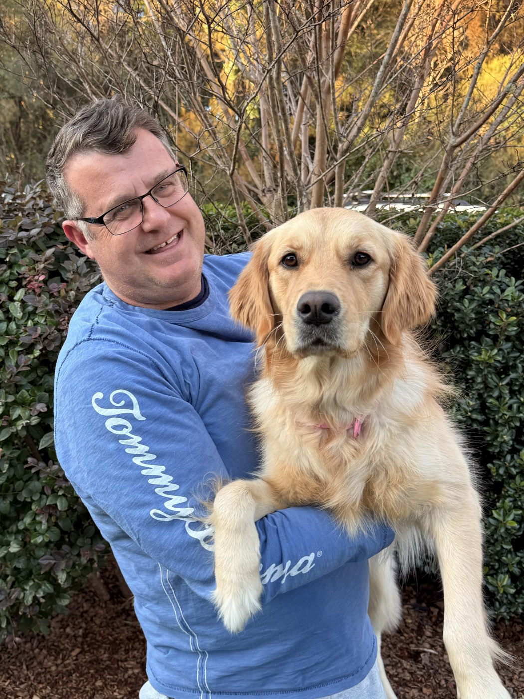 Matt, owner of Retriever Garden Care, holding his golden retriever