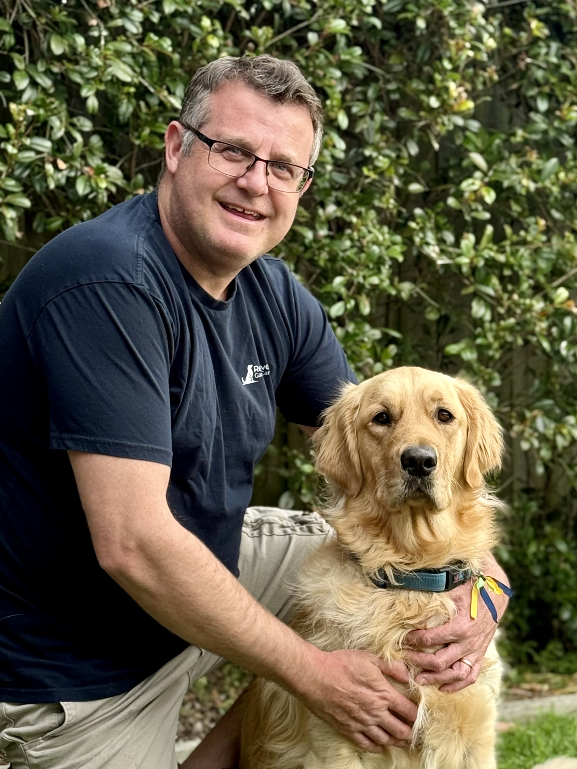 Matt, owner of Retriever Garden Care, holding his golden retriever
