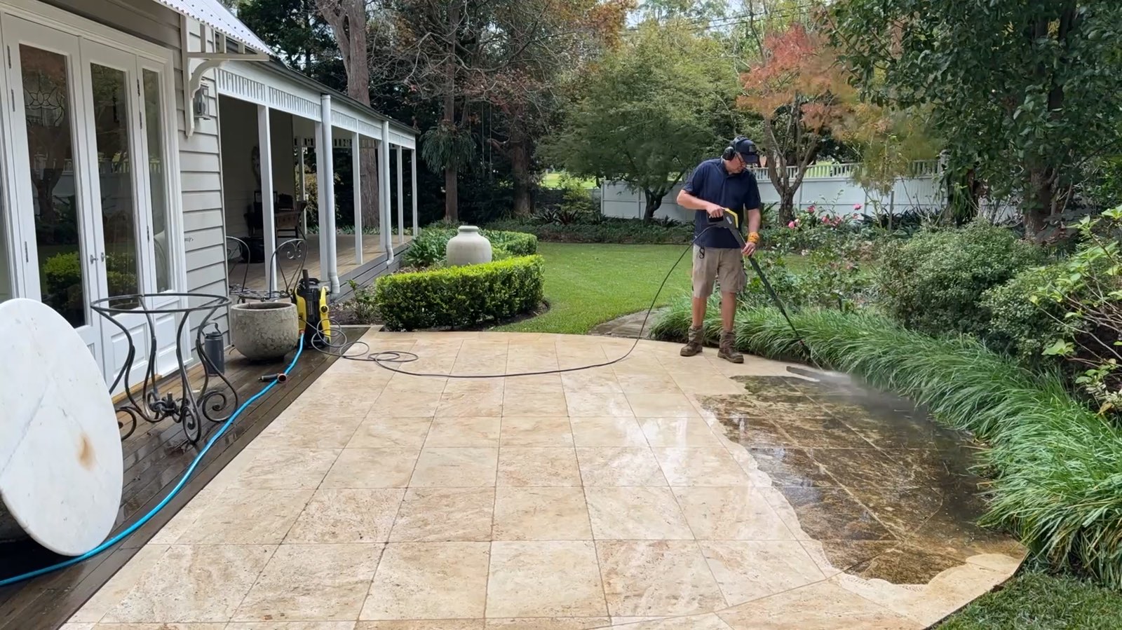 Stone patio being pressure washed, half clean and half still weathered